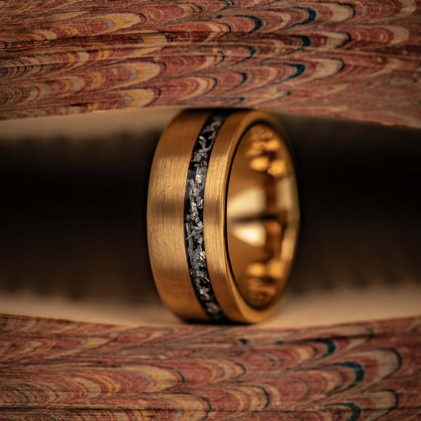 Mens yellow gold meteorite ring in-between pages of a book