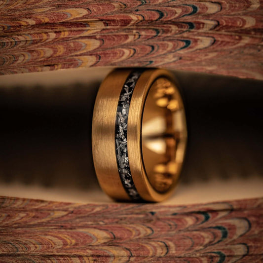Mens yellow gold meteorite ring in-between pages of a book