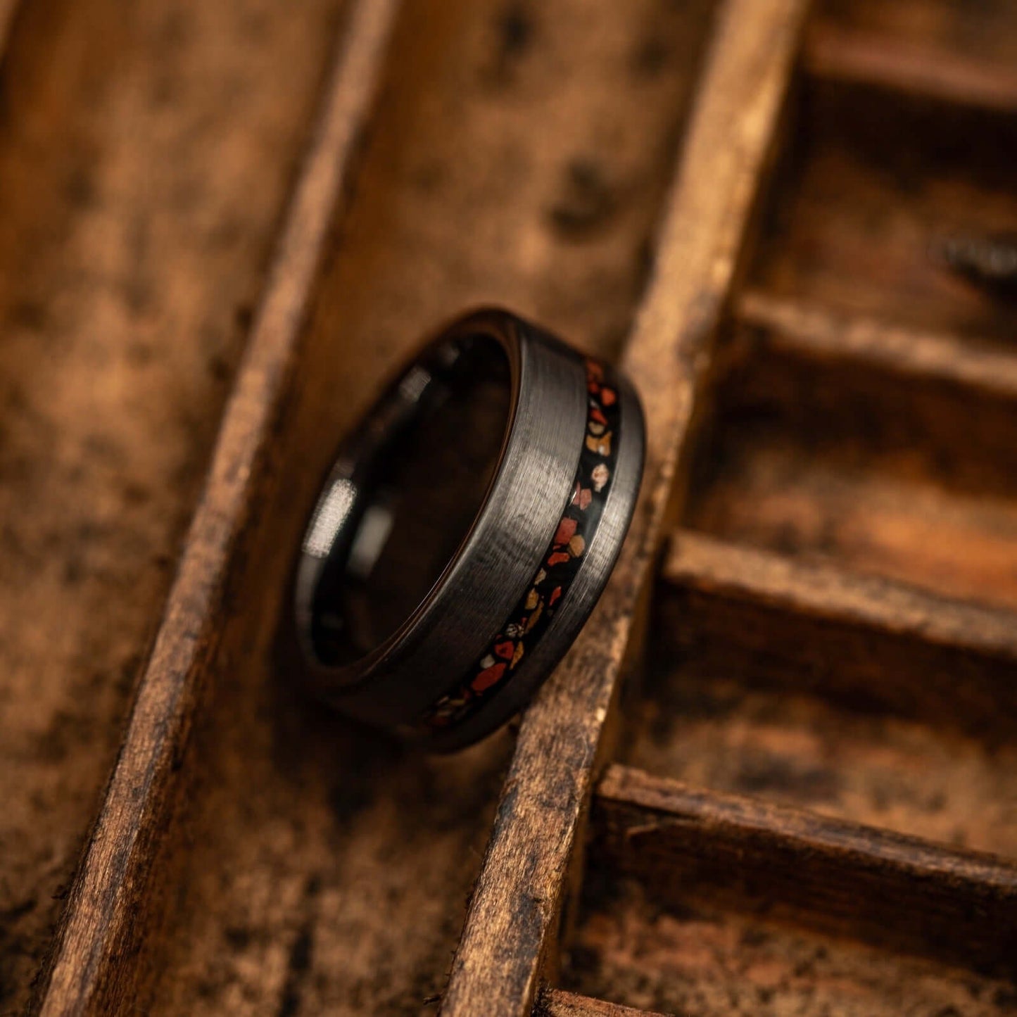 Unique brushed tungsten wedding ring with silver and red dinosaur bone accents.