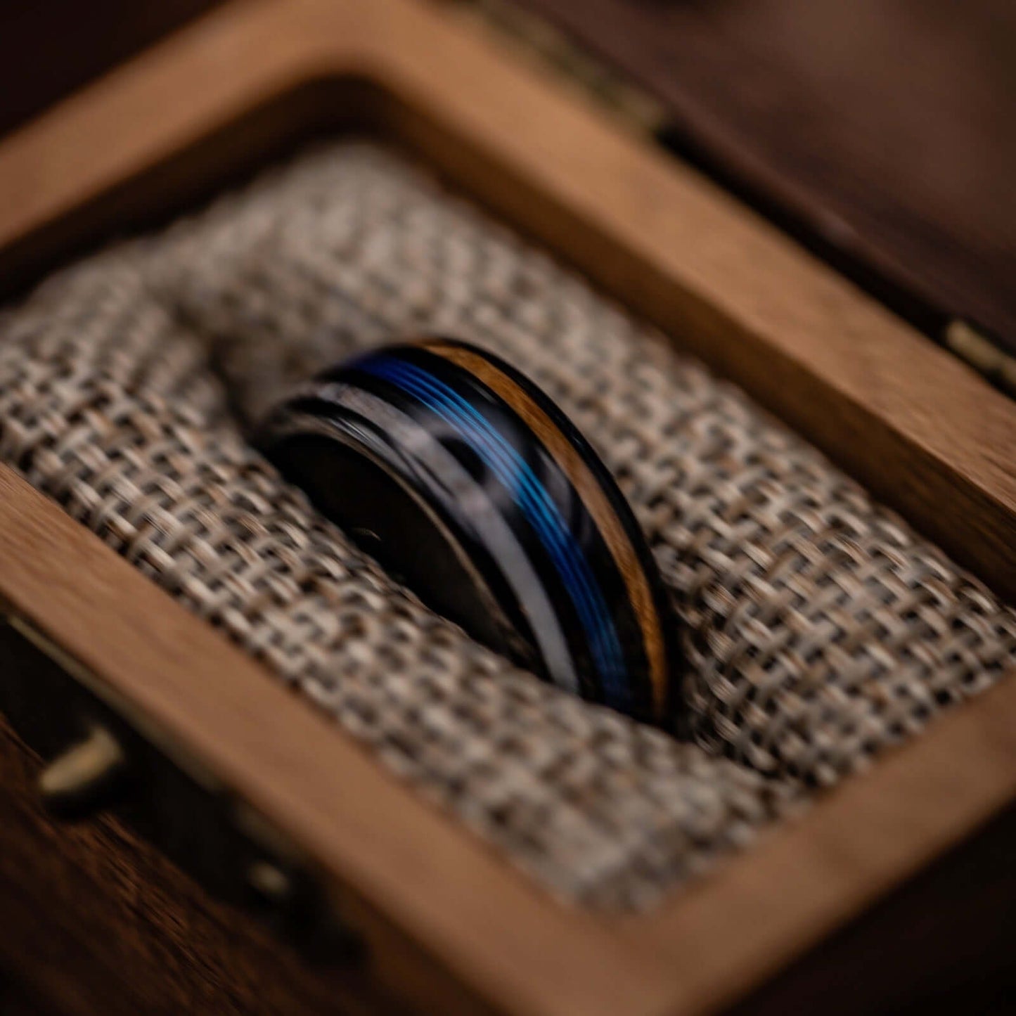 Outdoorsman's wedding ring adorned with antler, whiskey barrel wood, and blue fishing line elements.