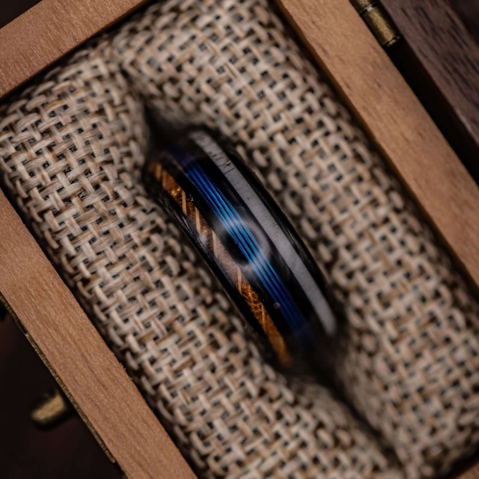 Whiskey barrel wood and antler ring with a blue fishing line motif, ideal for nature lovers.