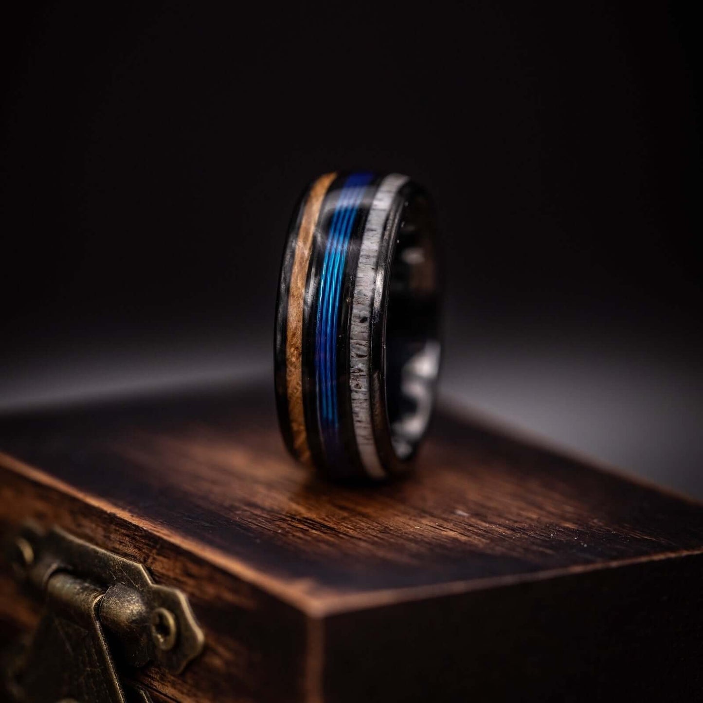 Distinctive fisherman's wedding band featuring antler and wood inlays, accented with blue fishing line.