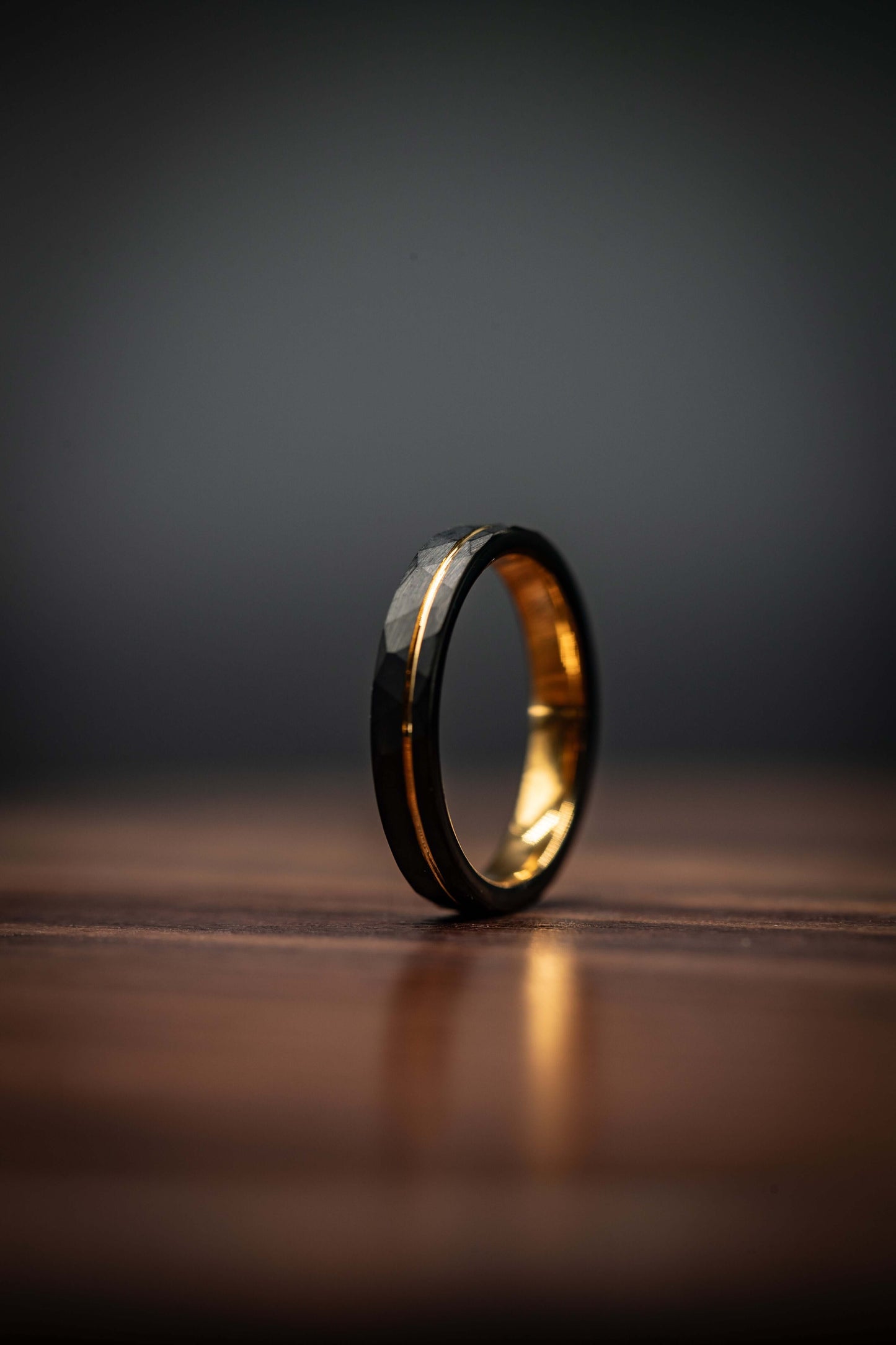 Yellow gold engagement ring featuring a hammered black band, offering a modern and unique design