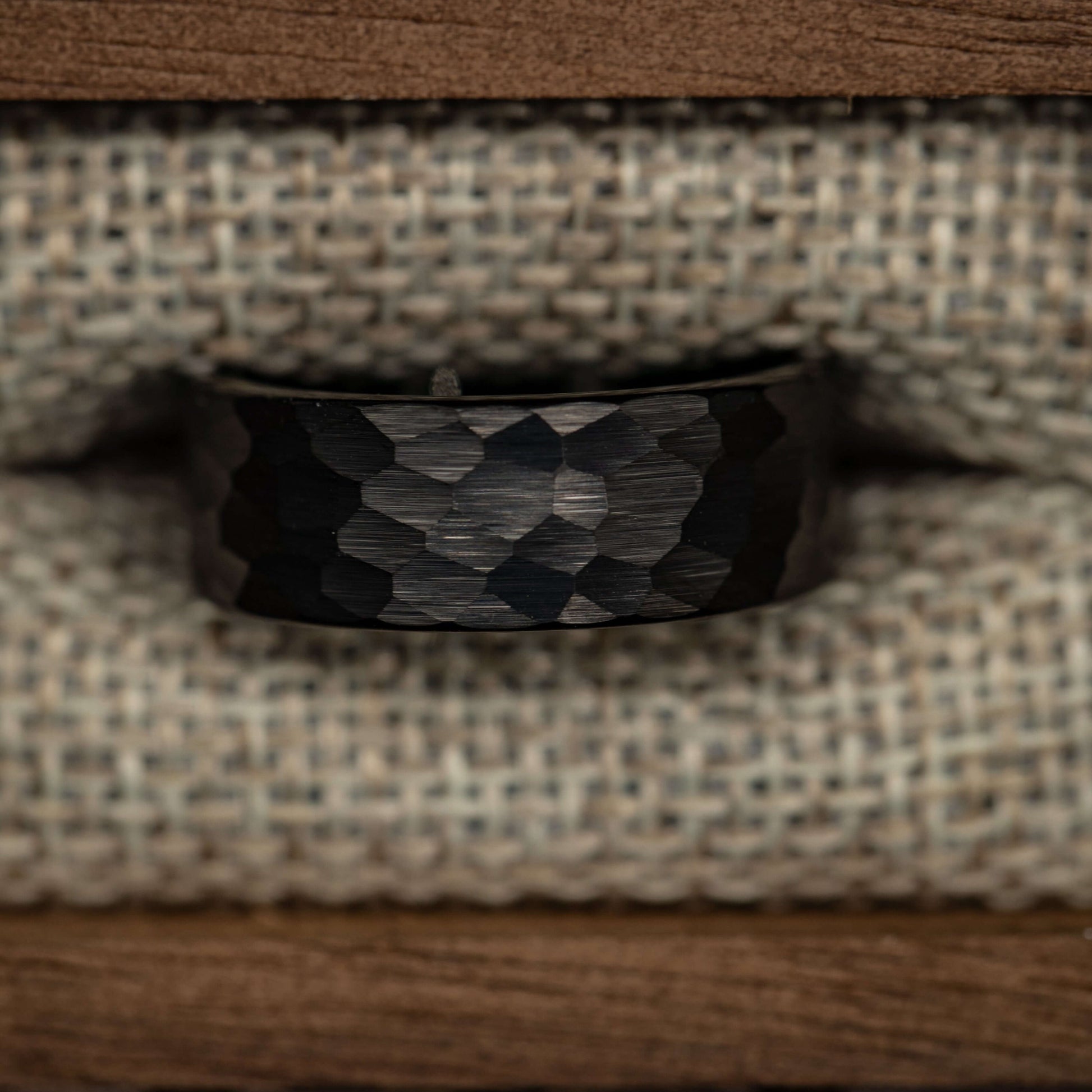 Hammered black tungsten wedding band, 8mm men's engagement ring, rustic design on linen background.
