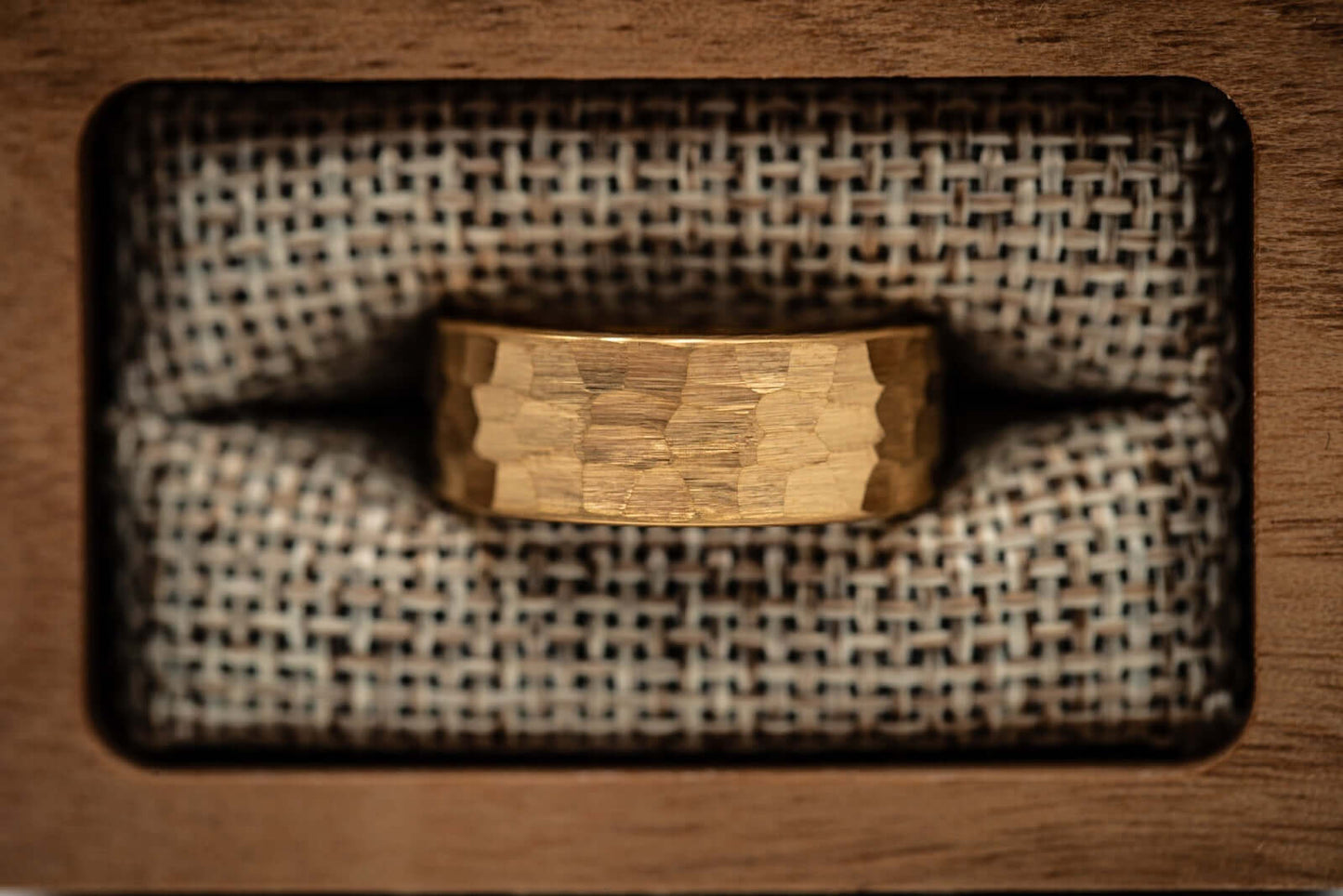 Men's 8mm width 18k Yellow Gold tungsten wedding ring inside walnut ring box in between burlap cushions