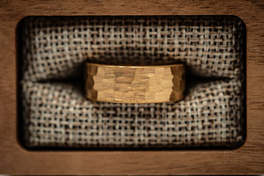 Men's 8mm width 18k Yellow Gold tungsten wedding ring inside walnut ring box in between burlap cushions