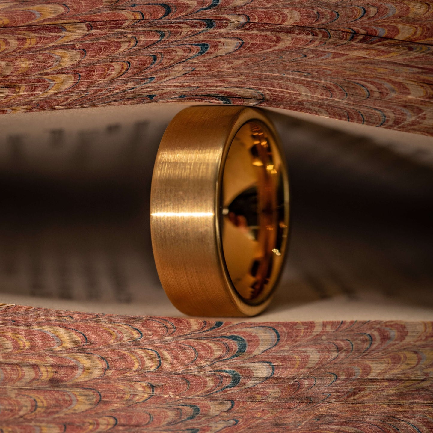 Gold brushed wedding ring displayed between pages of a decorative book, showcasing its unique design and finish.