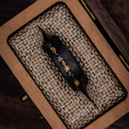 Unique black and gold wedding ring with meteorite and gold leaf detailing, perfect for special occasions.