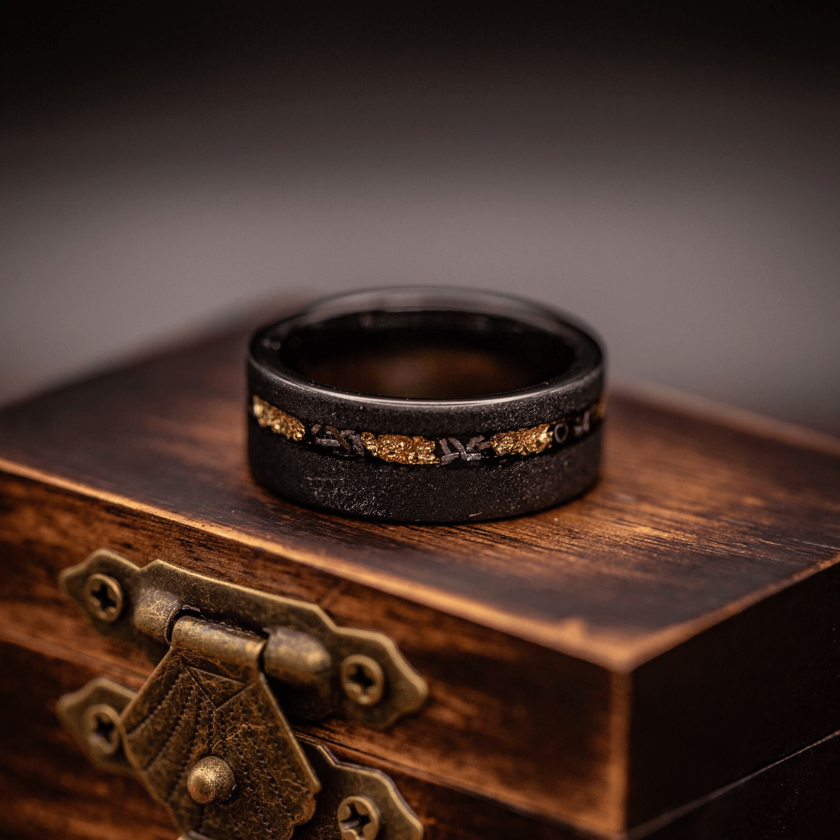 Men's wedding band showcasing a blend of black, gold, and meteorite elements for a distinctive look.