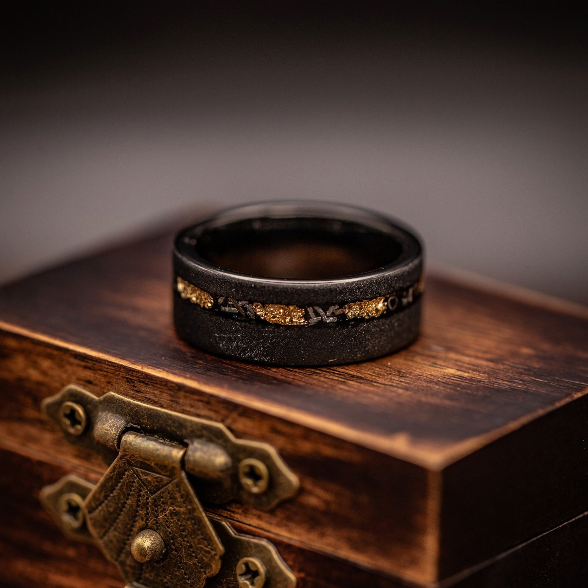 Men's wedding band showcasing a blend of black, gold, and meteorite elements for a distinctive look.