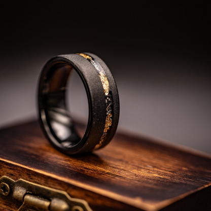 Elegant black and gold leaf wedding ring with meteorite inlay, offering timeless sophistication.