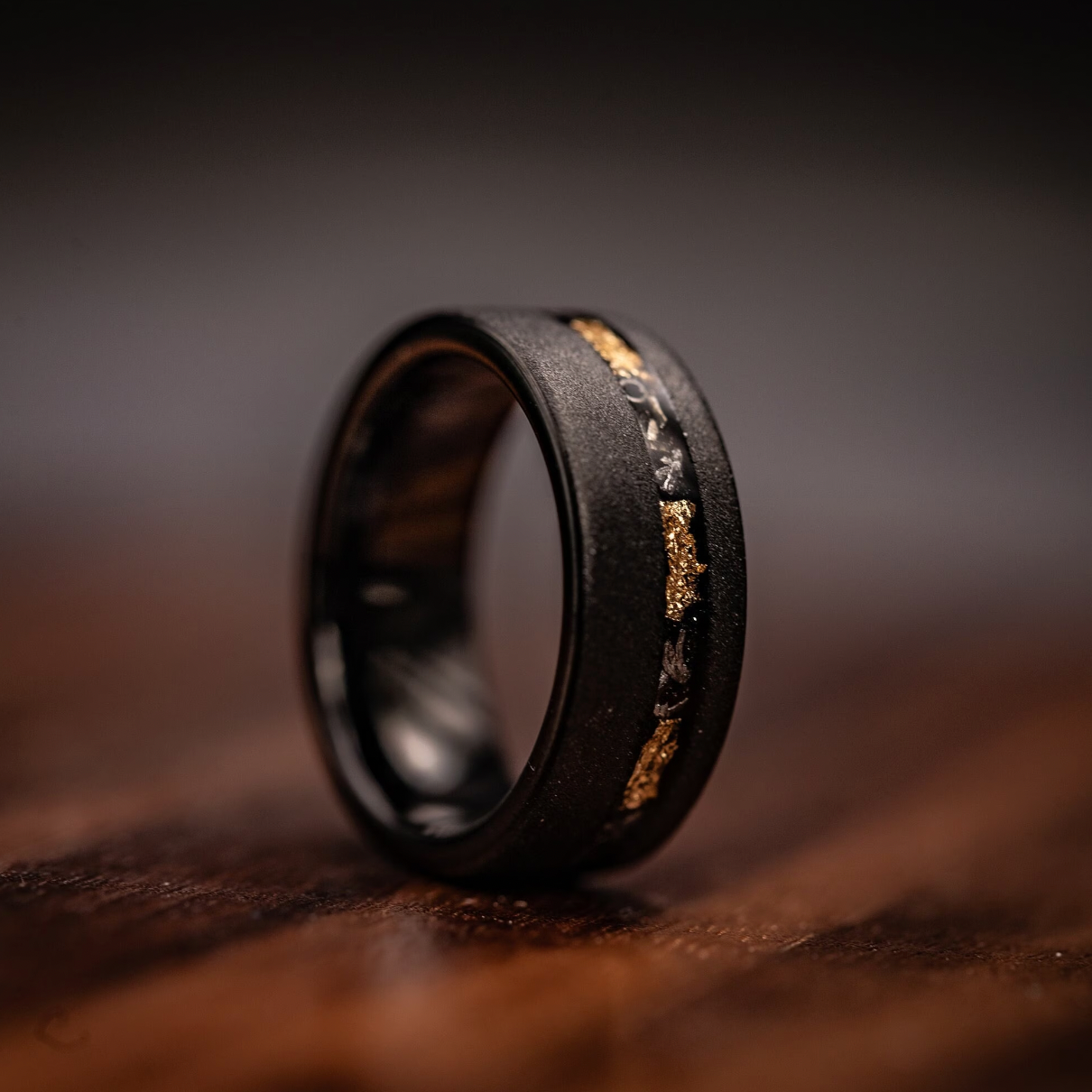 Handsome men's wedding band featuring black and gold accents, accented with meteorite and sandblasted finish.
