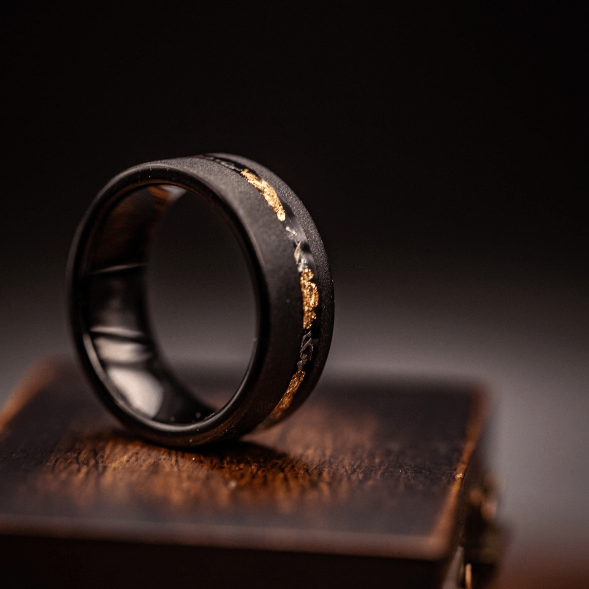 Exquisite black and gold meteorite ring with intricate gold leaf detailing, crafted for enduring style.