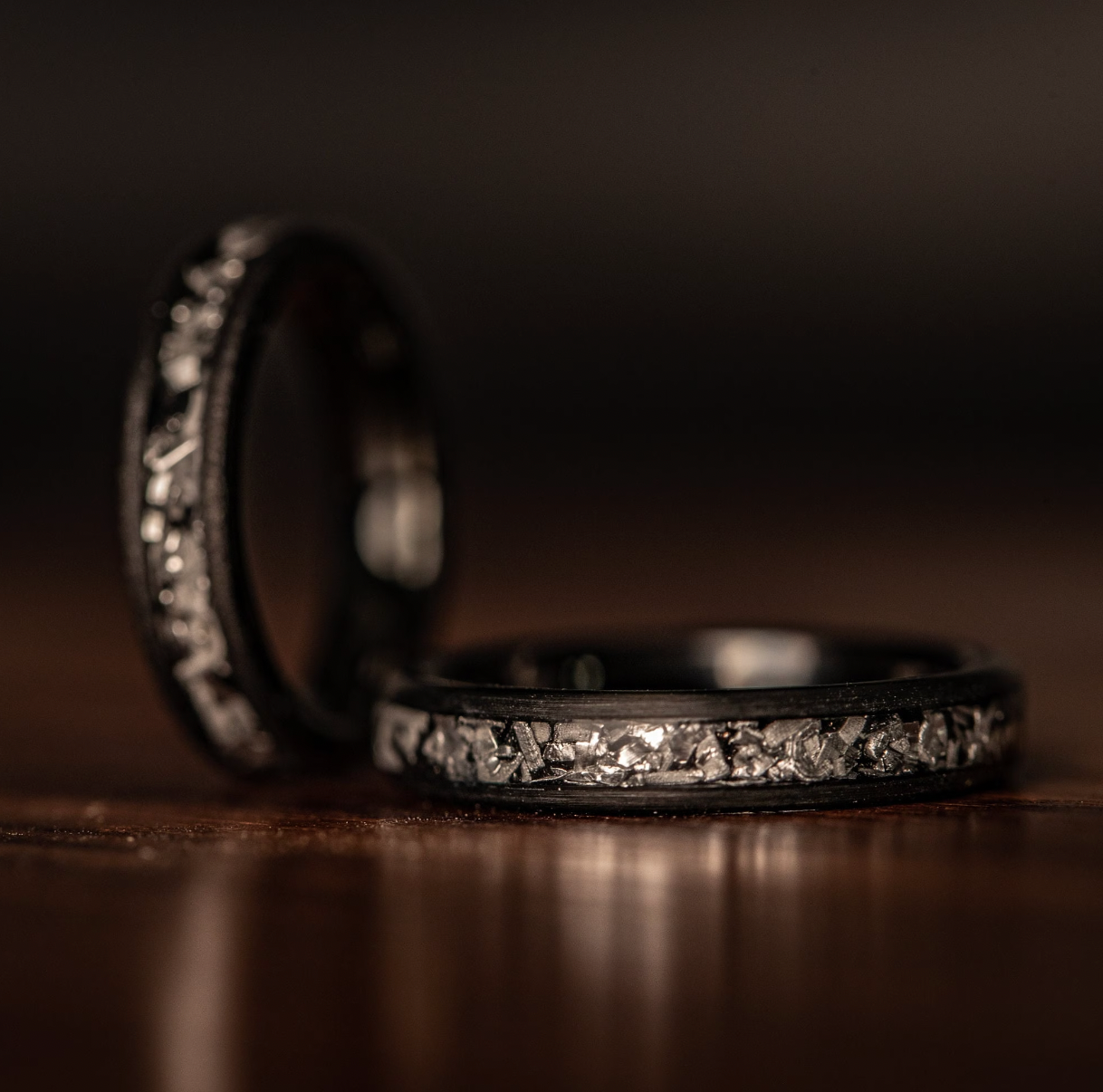 His and hers meteorite wedding bands, with a stylish black brushed design for her.