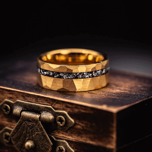 Mens 8mm hammered gold ring with meteorite inlay laying on ring box