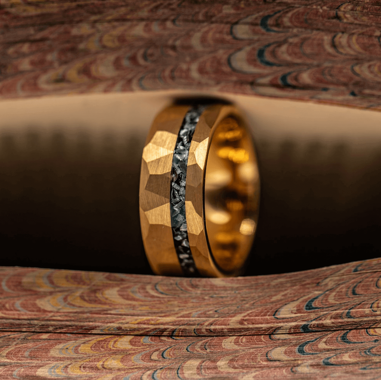 Hammered gold ring with meteorite inlay mens 8mm ring standing between pages of a book