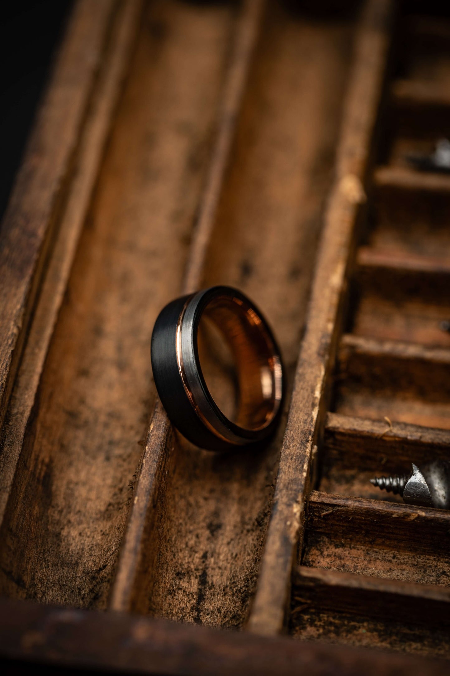 Black and silver wedding ring with rose gold inlay, hammered texture, unique men's wedding band, rustic background