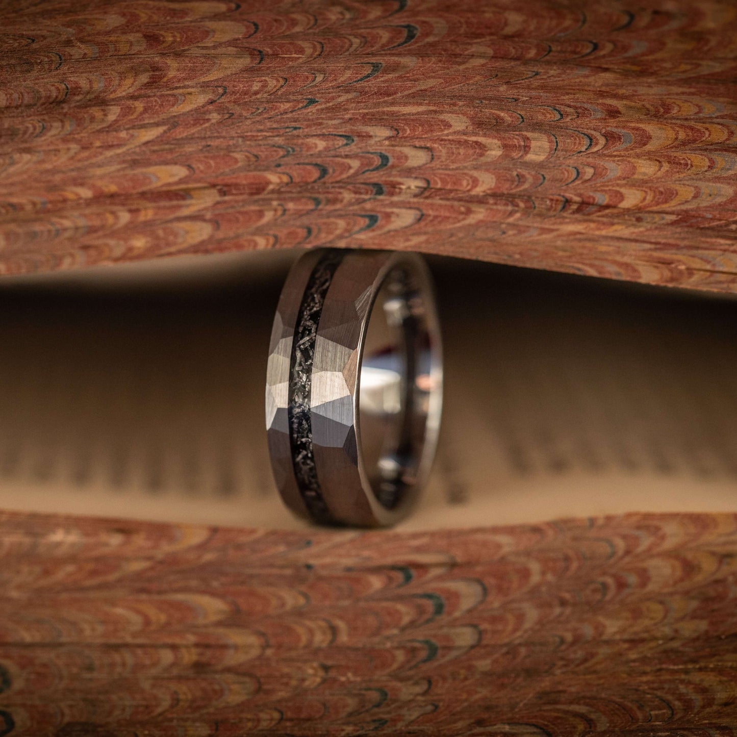 Silver hammered wedding band with Gibeon meteorite inlay on vintage book pages, featuring a bold rustic design.