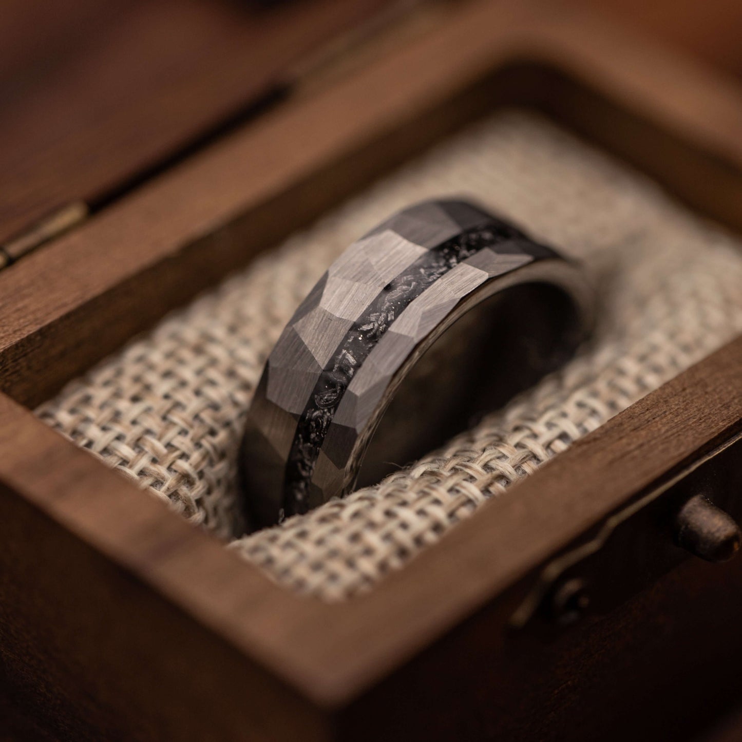 Silver hammered wedding band featuring Gibeon meteorite inlay, displayed in a wooden box.