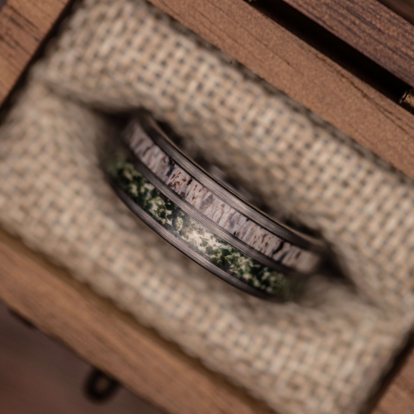 Mens deer antler and moss agate wedding band in a wooden box, showcasing its unique design and polished finish.