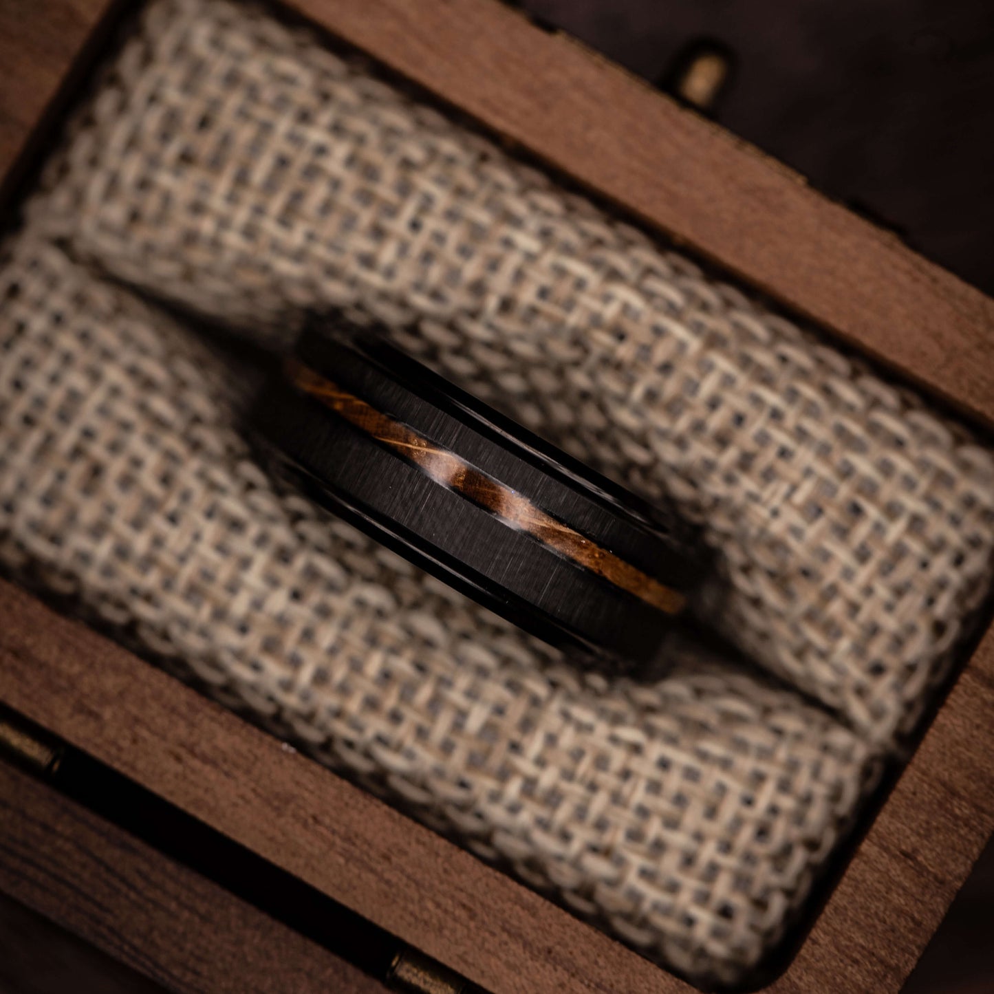 Black brushed tungsten ring featuring Koa wood inlay, elegantly displayed in a wooden box.