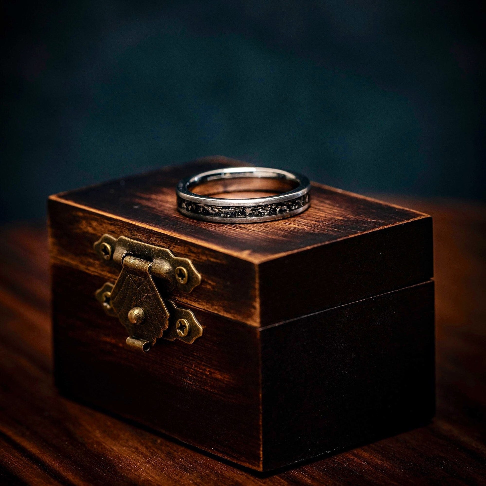 Silver Tungsten 4mm Wedding Ring laying on its side on top of a walnut ring box