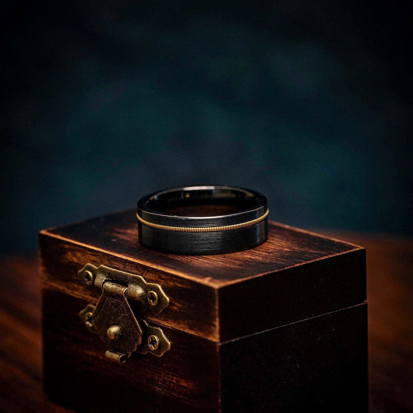 Black Wedding Band with Gold Guitar String inlay on top of walnut ring box