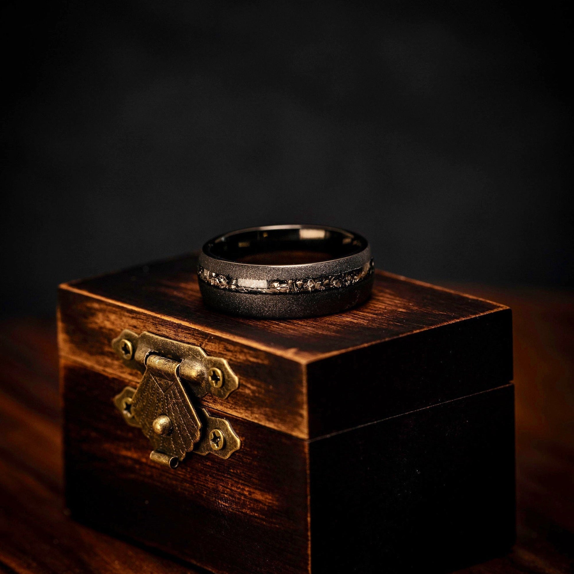 Contemporary black wedding band with meteorite detailing and sandblasted texture.