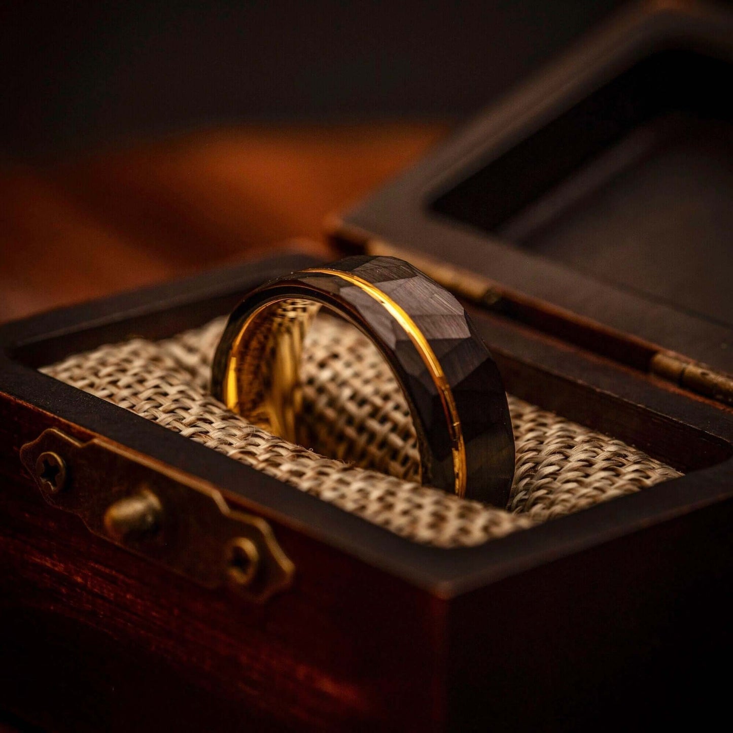 Elegant men's wedding band crafted from hammered black material and accented with yellow gold.
