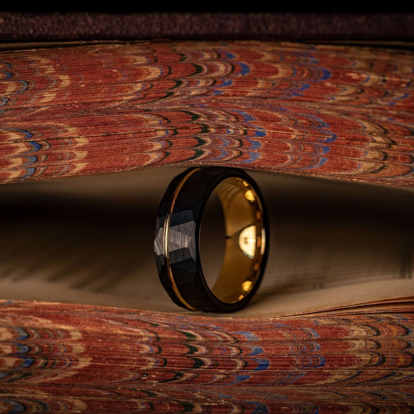 Striking black wedding band with hammered texture and elegant yellow gold detailing.