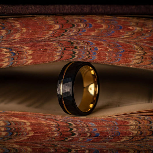 Striking black wedding band with hammered texture and elegant yellow gold detailing.