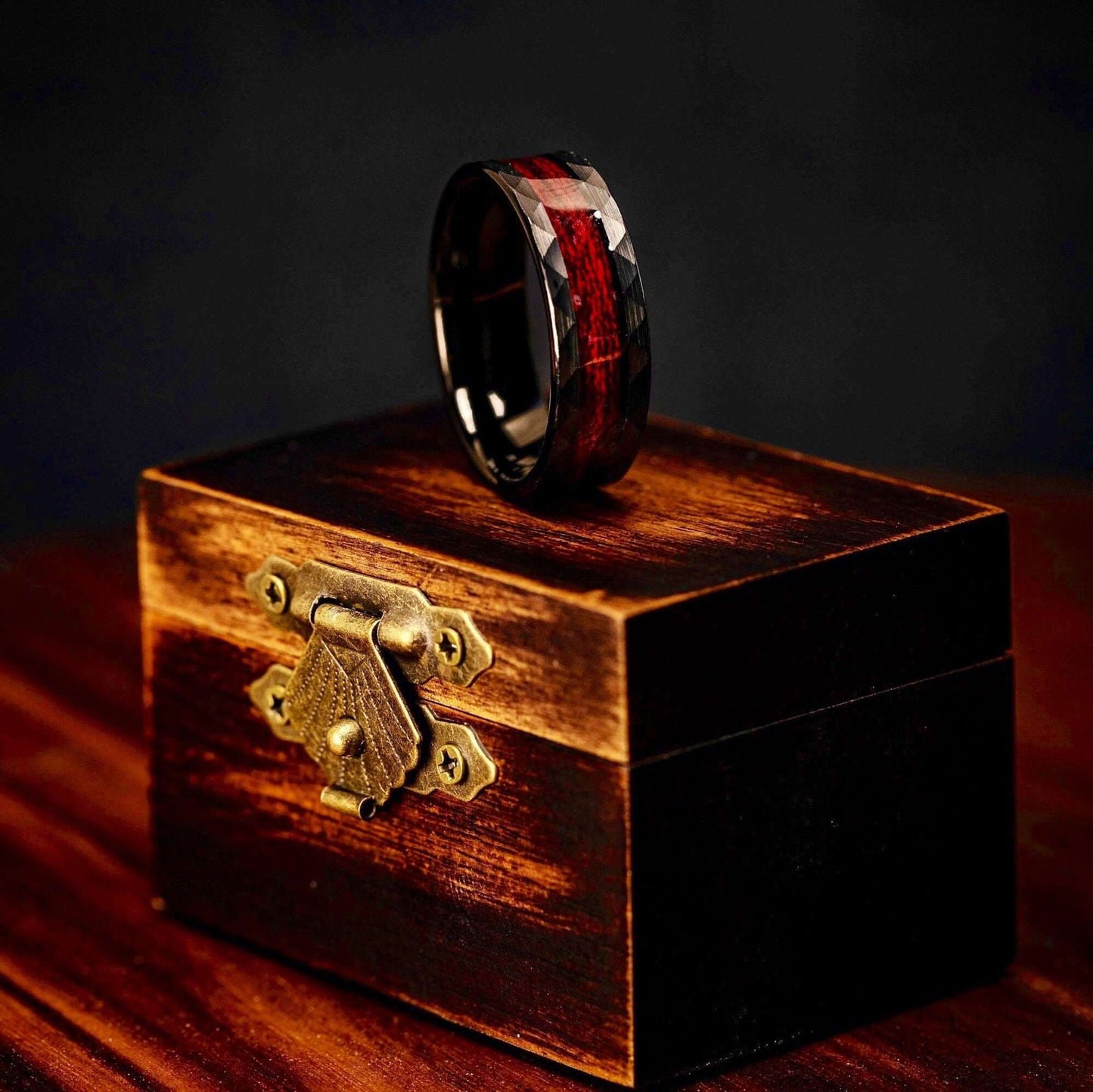 Black 8mm Hammered Wedding ring Set with Red Koa Wood Inlay standing on its side on top of walnut ring box