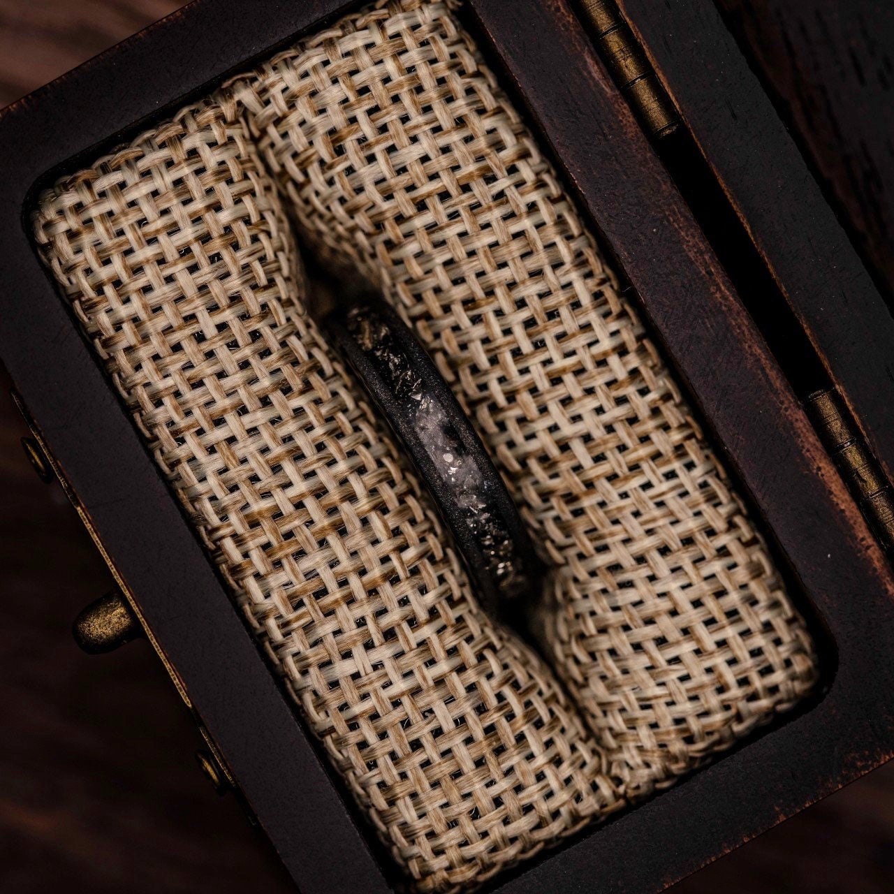 Women's Black Tungsten Wedding Ring with Meteorite inlay and Sandblasted finish inside walnut ring box between burlap cushions
