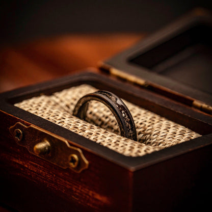 Women's Black Tungsten Wedding Ring with Meteorite inlay and Sandblasted finish inside walnut ring box between burlap cushions