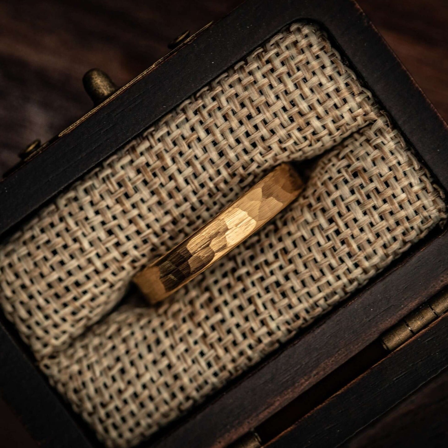 Women's 4mm Hammered Yellow Gold Tungsten Wedding Ring inside walnut ring box between burlap cushions