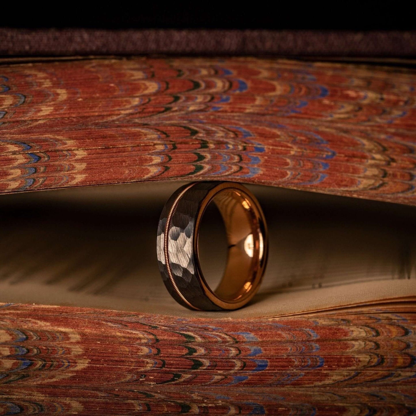 Men's wedding band with hammered rose gold and silver, featuring guitar string detail.