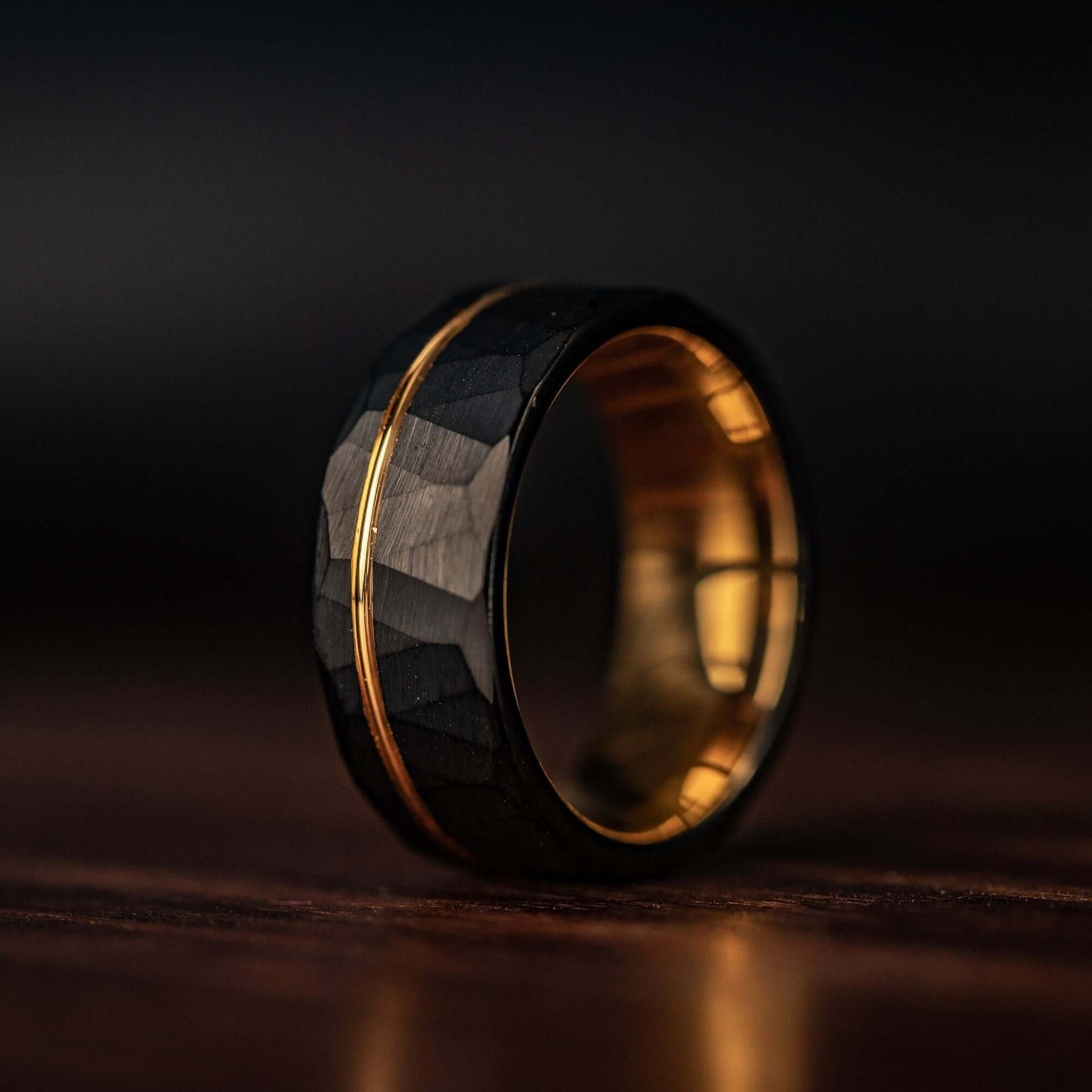 Hammered Black Tungsten Wedding Ring with Polished Rose Gold Inner Band standing on its side