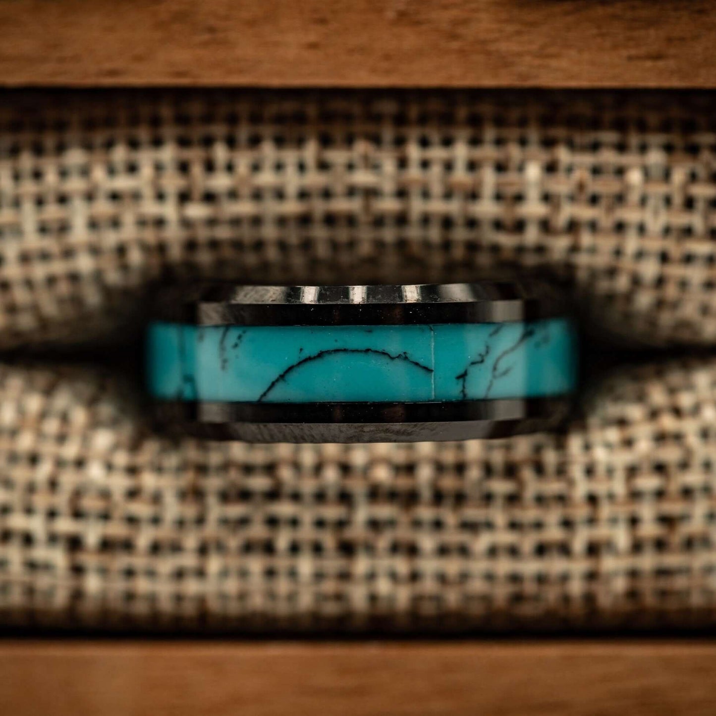 Black tungsten ring with beveled edges and turquoise inlay inside ring box