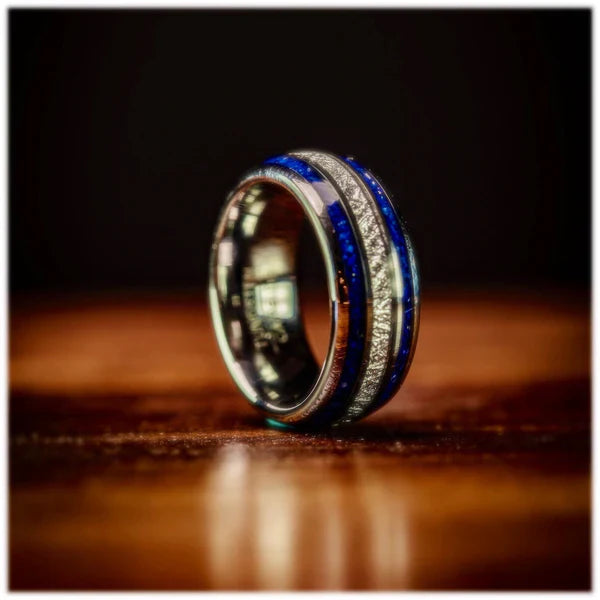 Unique silver meteorite wedding ring with blue and silver accents, elegantly displayed on a dark background.