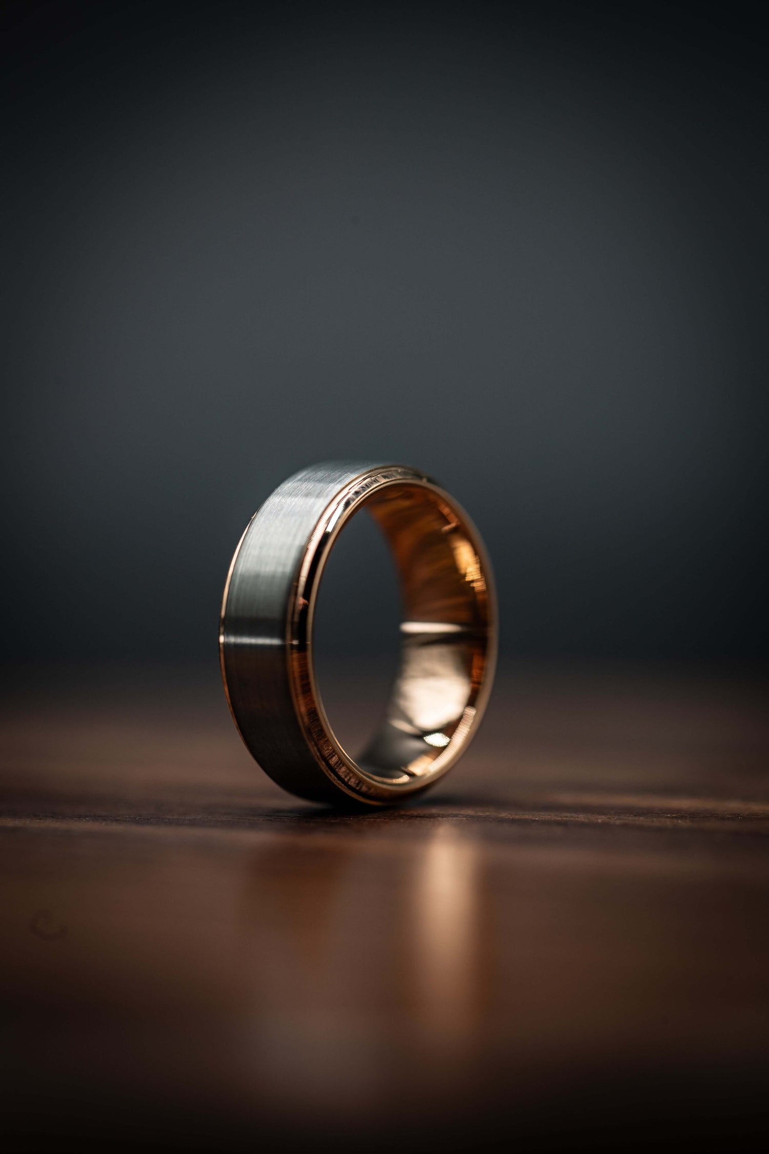 Unique handcrafted gold and meteorite men's ring for weddings, engagements, or everyday style on wooden surface.