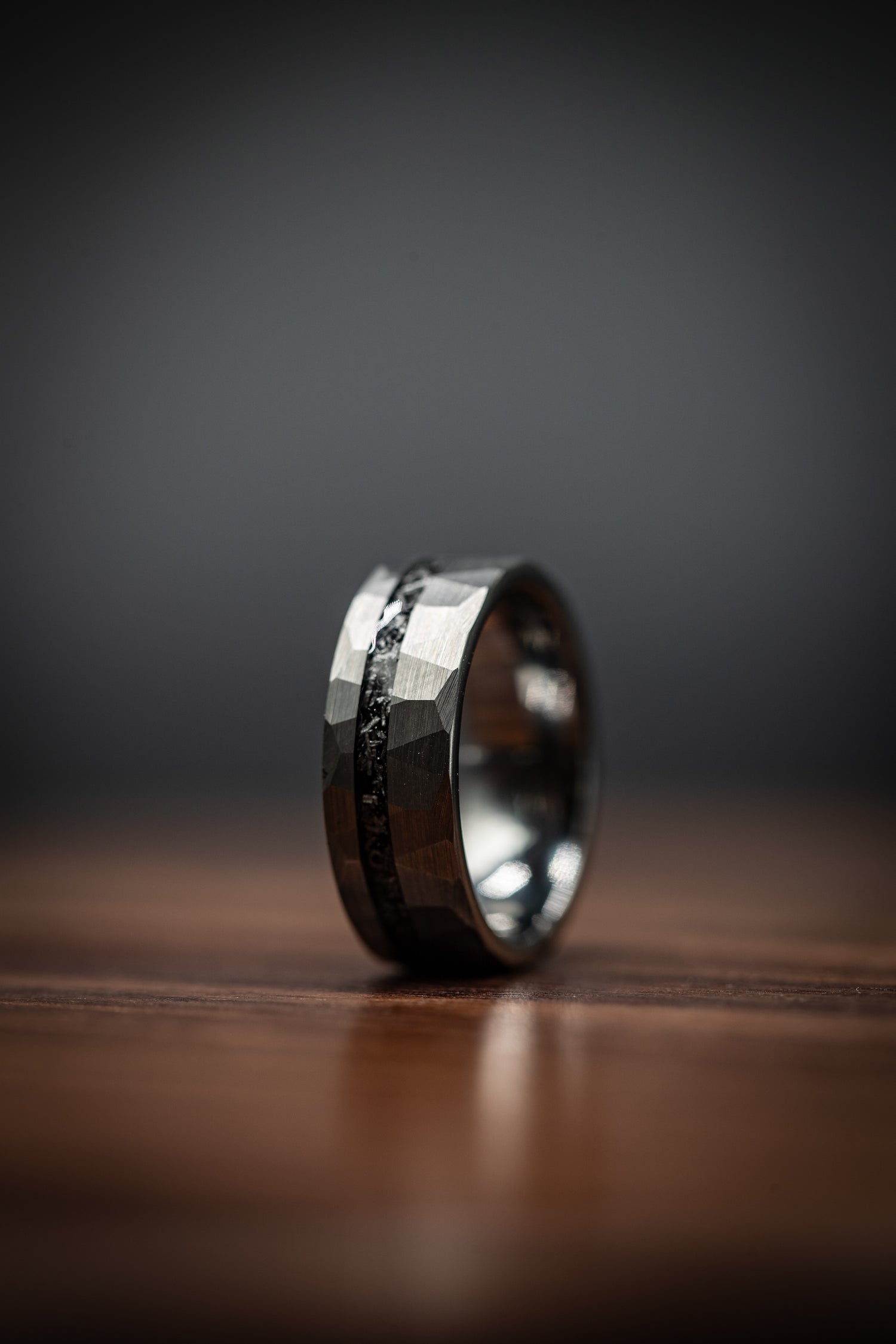Unique meteorite ring with gold accents on wooden surface, perfect for weddings, engagements, or everyday style. Free standard shipping available.