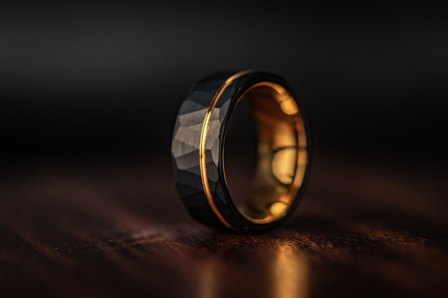 Handcrafted black and gold tungsten ring on a wooden surface