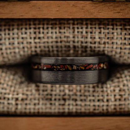 Silver wedding band adorned with vivid red dinosaur bone, perfect for fossil enthusiasts.