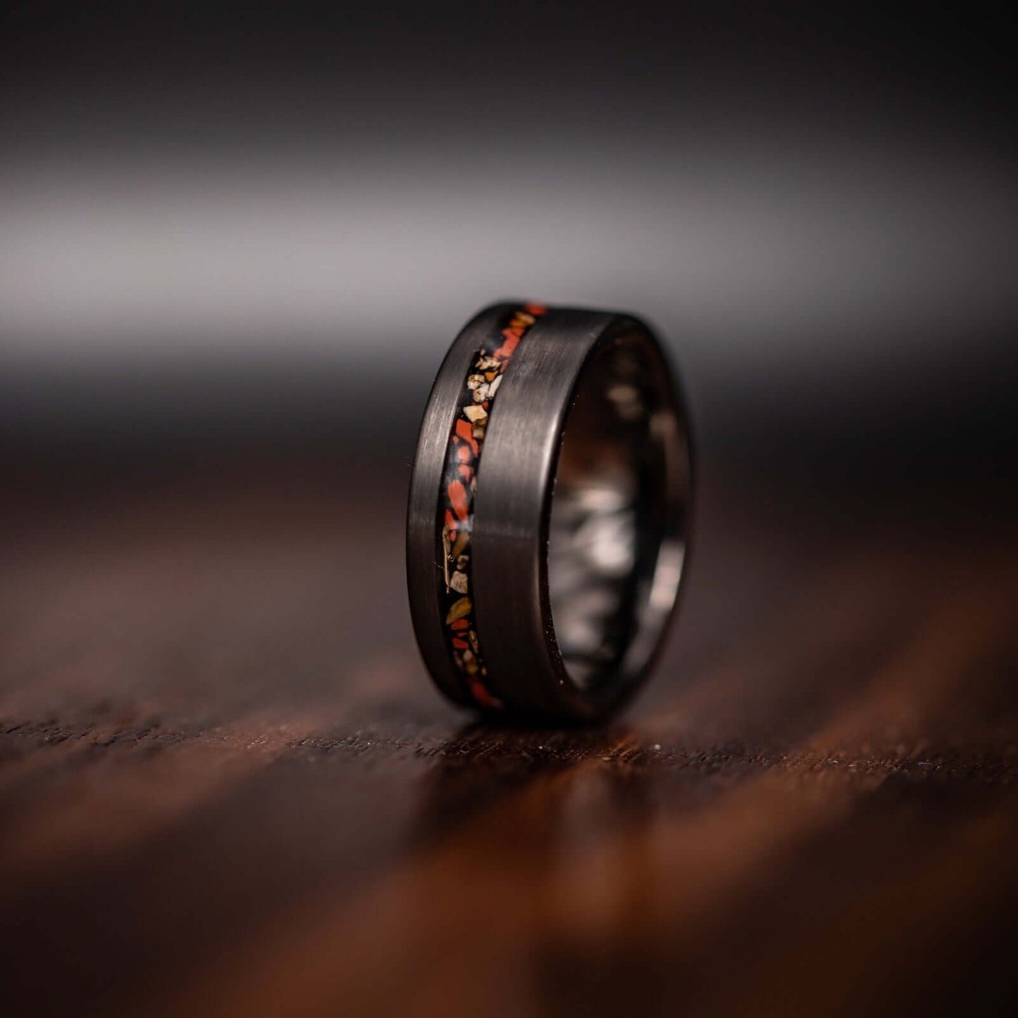 Striking silver wedding band with red dinosaur bone inlay, featuring T-Rex bone detail.