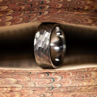 Hammered silver tungsten wedding band showcased on a colorful marbled background, highlighting its unique texture and shine.