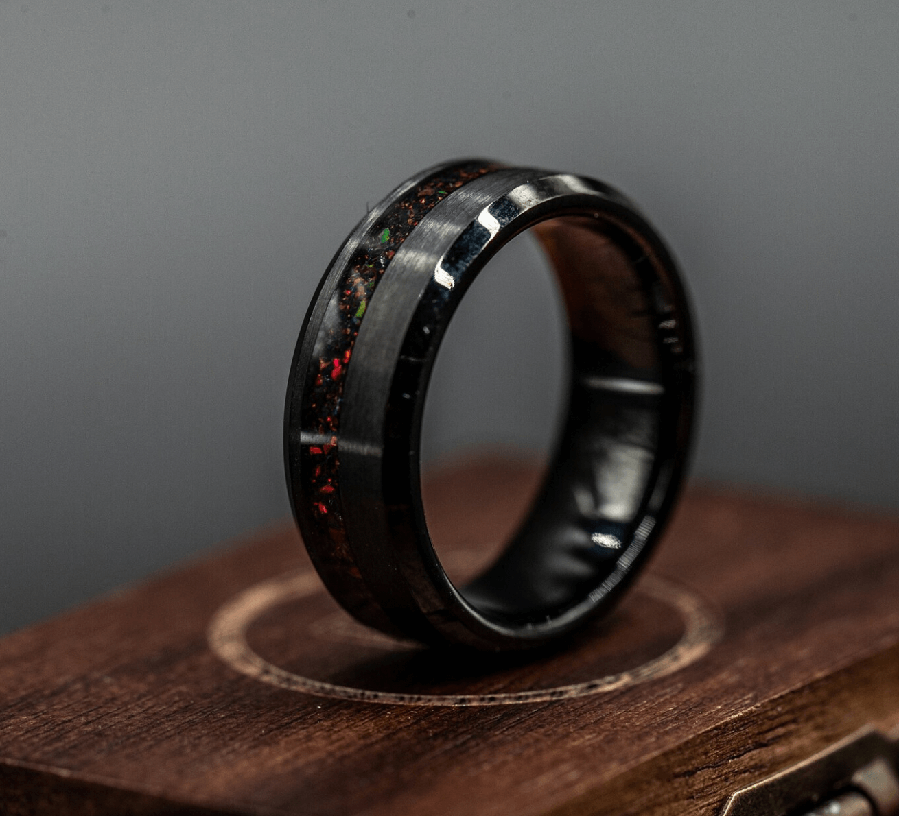 Black brushed tungsten ring with a channel of black fire opal, showcasing modern elegance and durability.