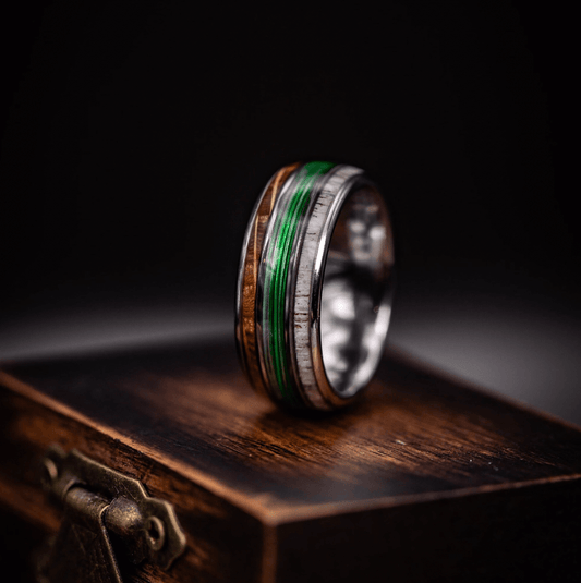 Fishing line wedding ring featuring antler and whiskey barrel wood on a wooden box. Unique outdoorsman jewelry.