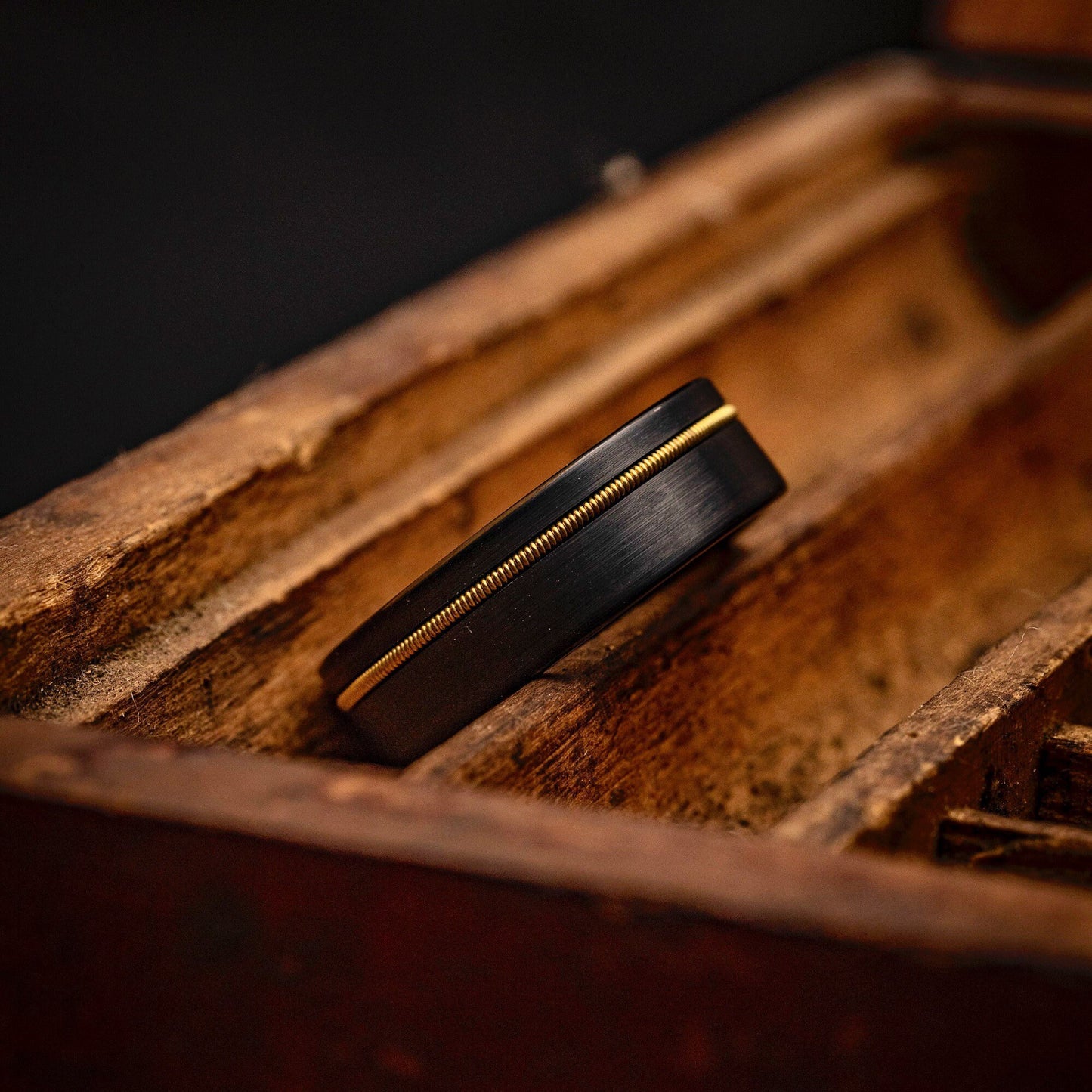 8mm Black Tungsten Wedding Ring with Gold Guitar String wrap inside an old wooden box