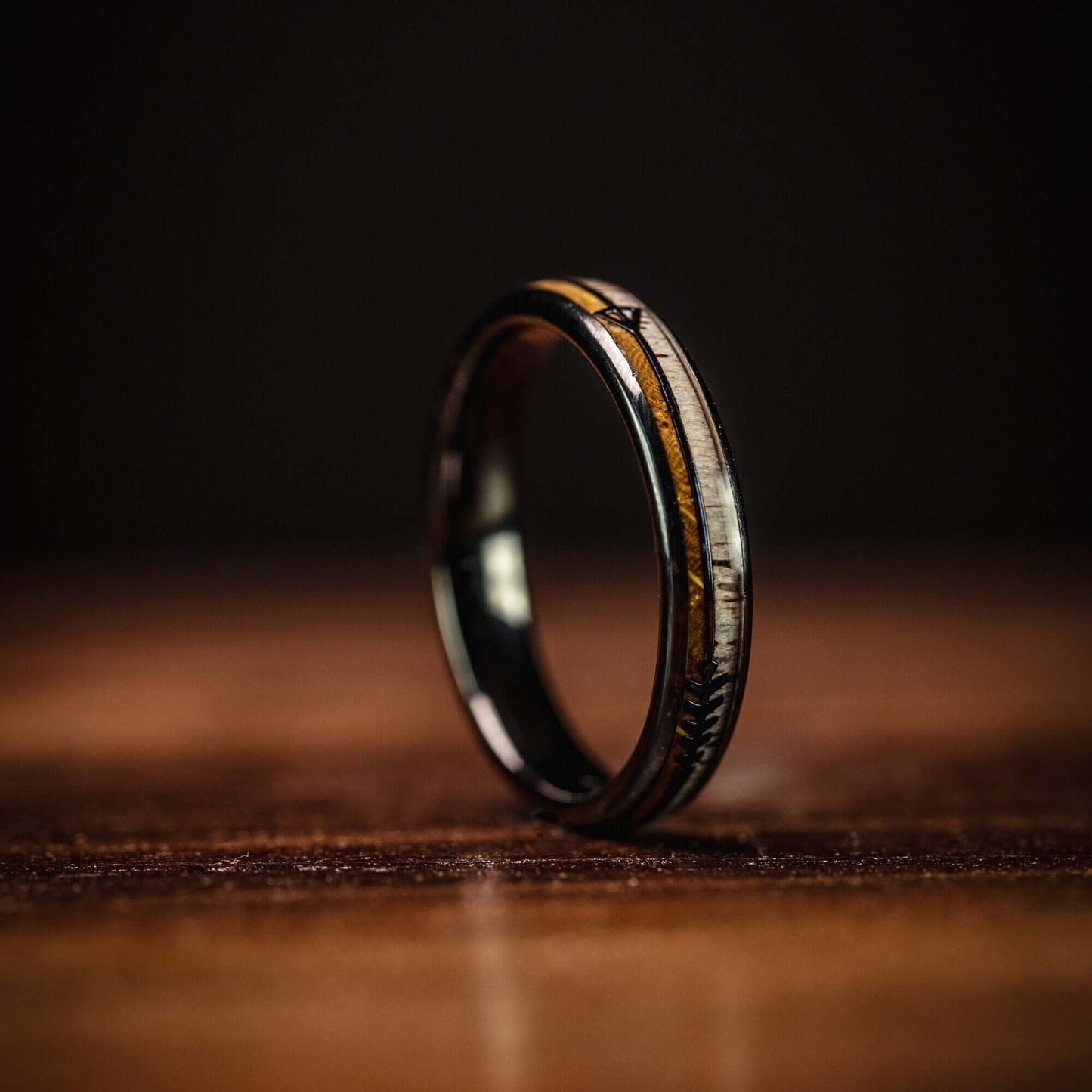 Women's 4mm wedding ring with whiskey barrel wood and deer antler inlay standing on its side