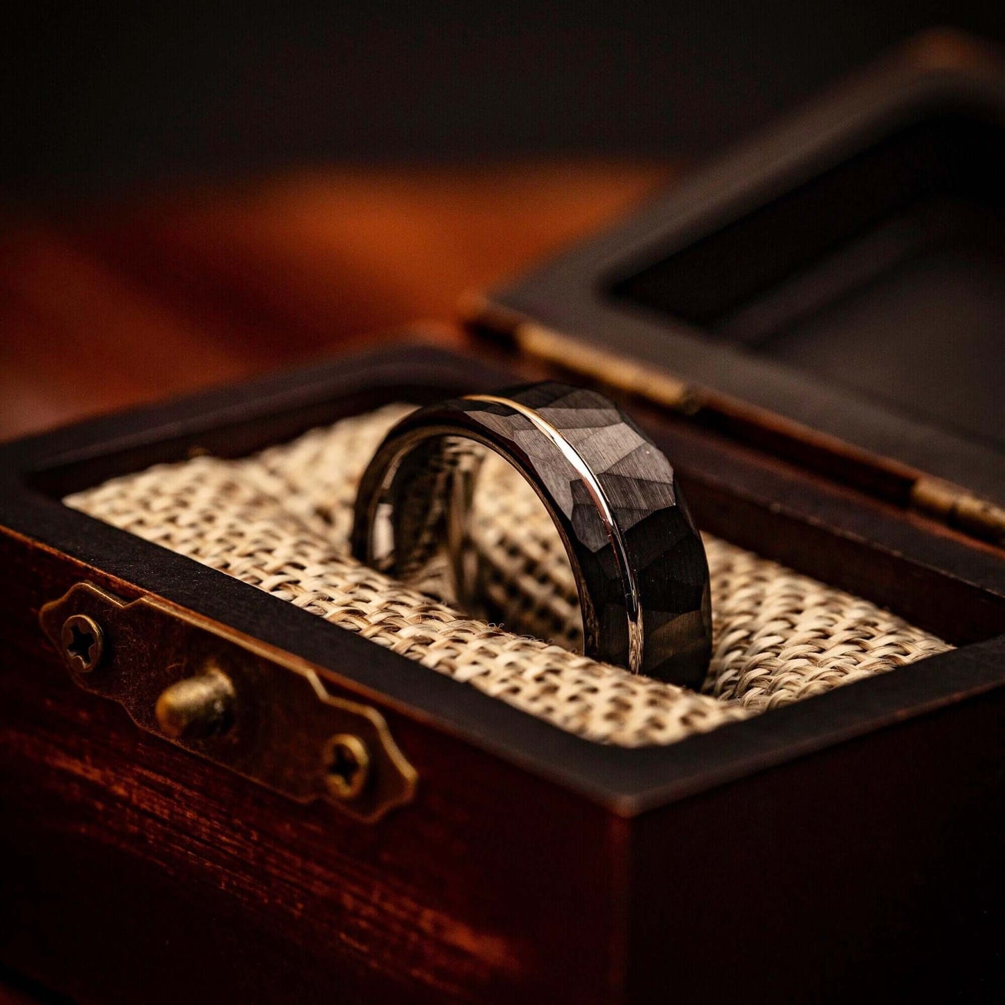 Hammered Black Tungsten Wedding Band with Silver Channel Inlay and Polished Silver Inner Band inside walnut ring box between burlap cushions